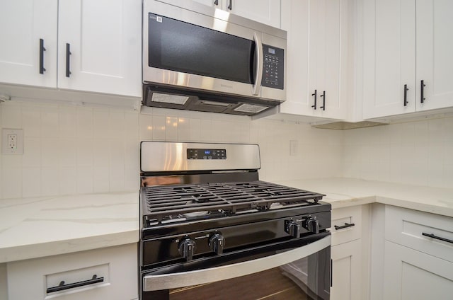 kitchen with white cabinets, light stone counters, tasteful backsplash, and stainless steel appliances