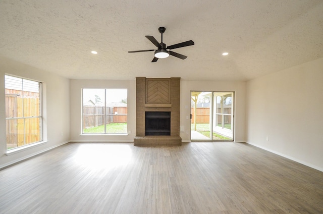 unfurnished living room featuring baseboards, a textured ceiling, wood finished floors, and a fireplace