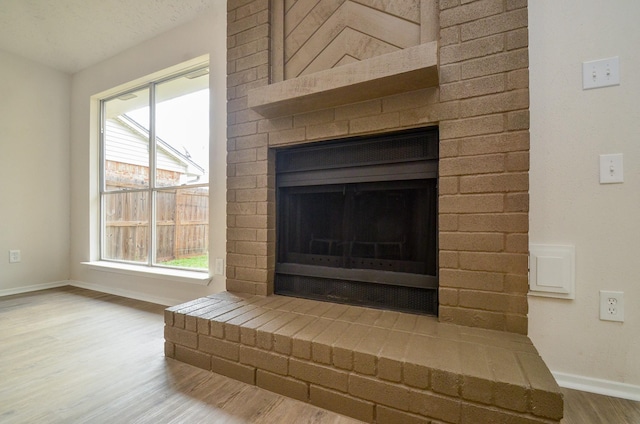 details with baseboards, a brick fireplace, and wood finished floors