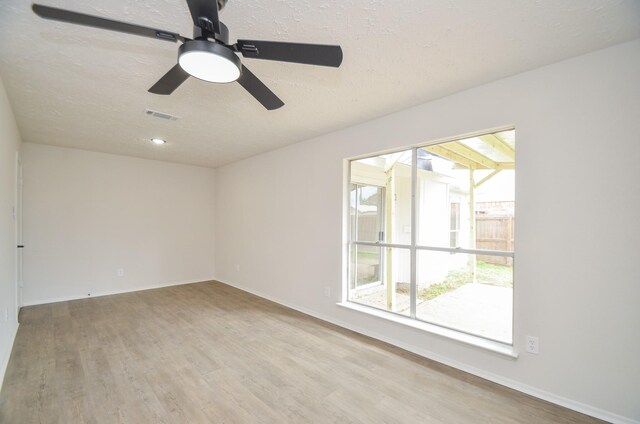 unfurnished room featuring visible vents, a textured ceiling, baseboards, and wood finished floors