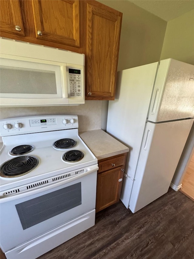 kitchen with white appliances, brown cabinetry, light countertops, and dark wood-style flooring