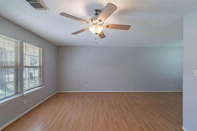 spare room with visible vents, baseboards, ceiling fan, light wood-style floors, and a textured ceiling