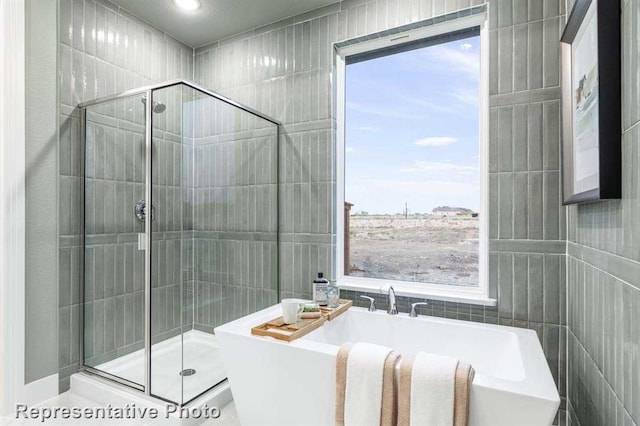 full bathroom featuring a freestanding bath, tile walls, and a shower stall