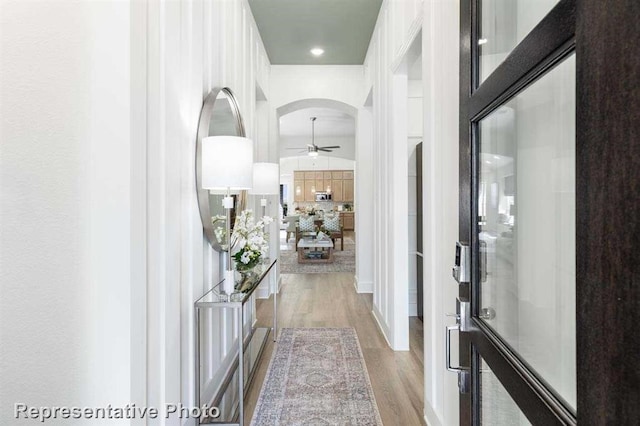 foyer featuring wood finished floors, arched walkways, and ceiling fan