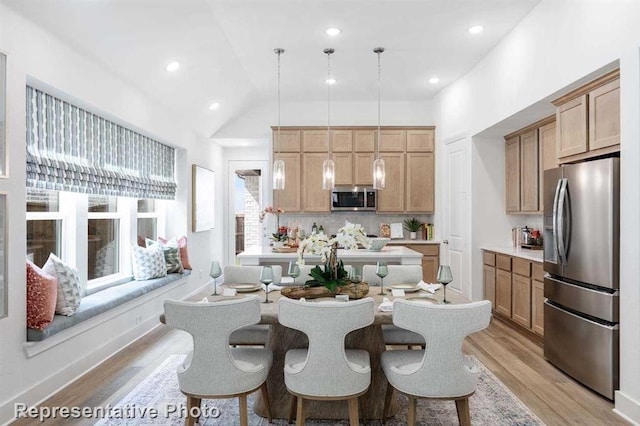 interior space featuring lofted ceiling, light wood-style flooring, light countertops, appliances with stainless steel finishes, and tasteful backsplash