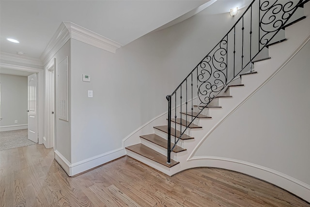 stairway featuring baseboards, wood finished floors, and ornamental molding