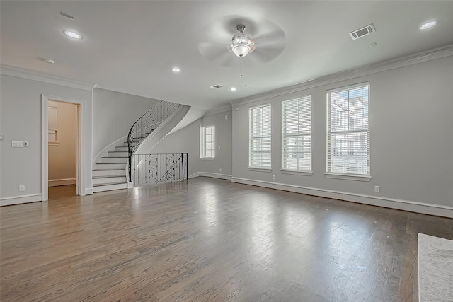unfurnished living room with wood finished floors, baseboards, visible vents, ornamental molding, and stairs