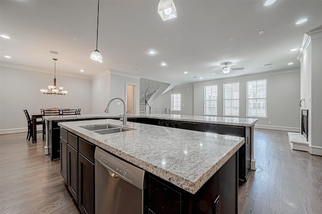 kitchen with a sink, crown molding, a center island with sink, wood finished floors, and stainless steel dishwasher