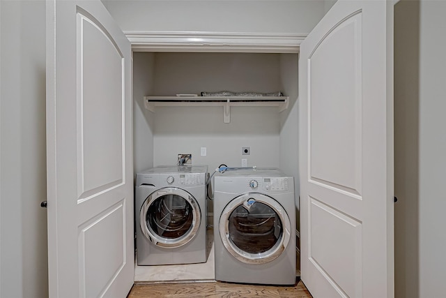 washroom featuring washer and dryer, laundry area, and light wood finished floors