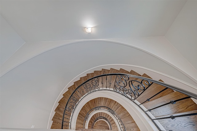 stairway featuring arched walkways and lofted ceiling