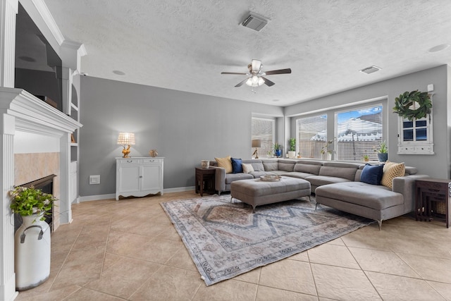 living area featuring light tile patterned flooring, visible vents, a tile fireplace, and a textured ceiling