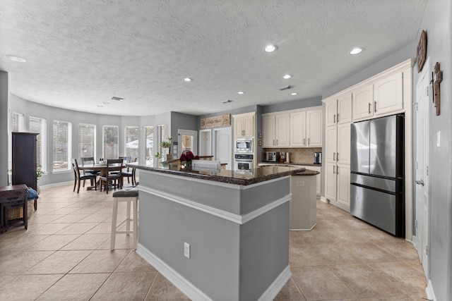 kitchen with a kitchen island, a kitchen bar, decorative backsplash, recessed lighting, and appliances with stainless steel finishes