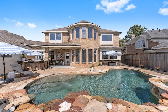 back of house with outdoor dry bar, a fenced in pool, an in ground hot tub, and a fenced backyard