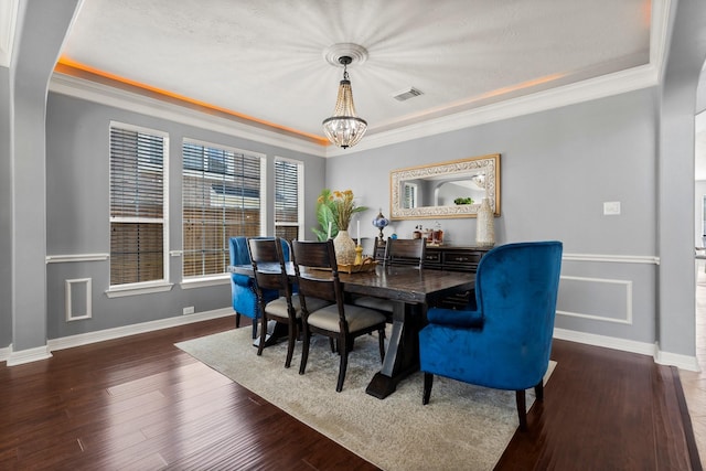 dining space featuring visible vents, ornamental molding, wood finished floors, baseboards, and a chandelier