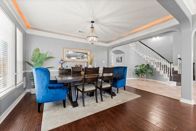 dining area featuring visible vents, ornamental molding, wood finished floors, stairway, and arched walkways