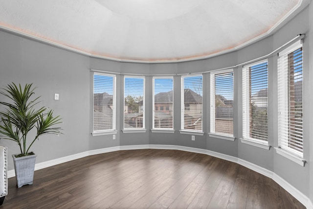 unfurnished room featuring a wealth of natural light, baseboards, and dark wood-style flooring