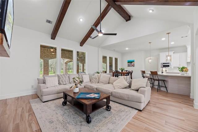 living area with visible vents, high vaulted ceiling, beam ceiling, light wood-style flooring, and ceiling fan