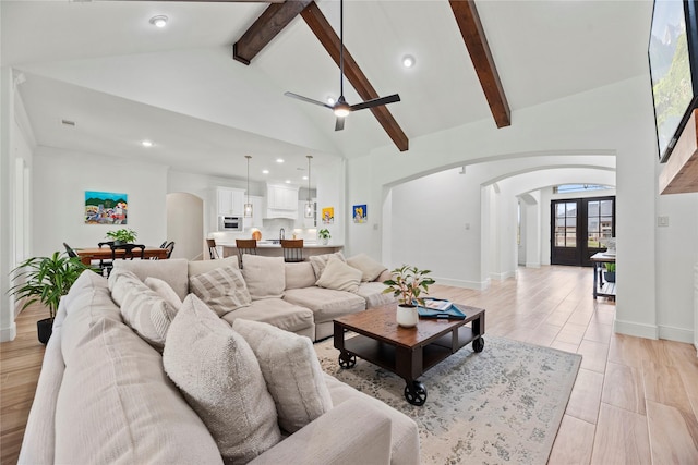 living area featuring baseboards, high vaulted ceiling, arched walkways, french doors, and beamed ceiling