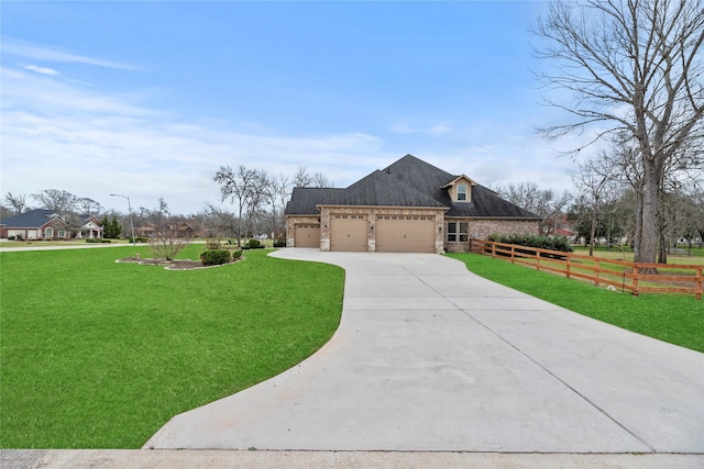 view of front of home with fence, an attached garage, a front lawn, concrete driveway, and stone siding