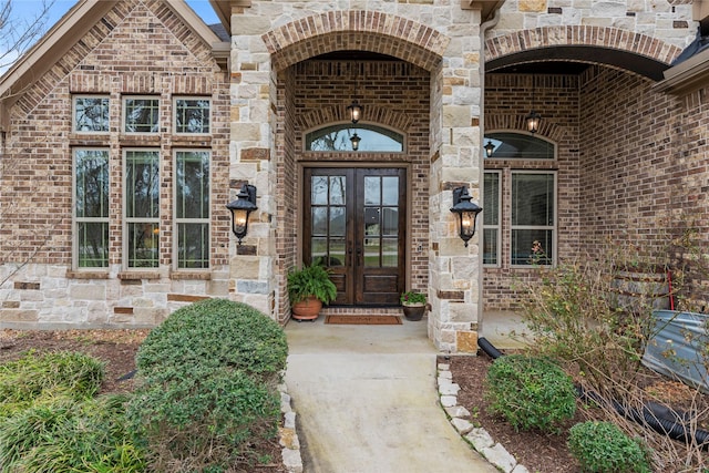 doorway to property featuring french doors, stone siding, and brick siding