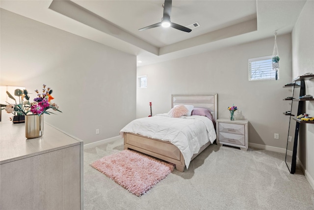 bedroom with light carpet, visible vents, a raised ceiling, and baseboards