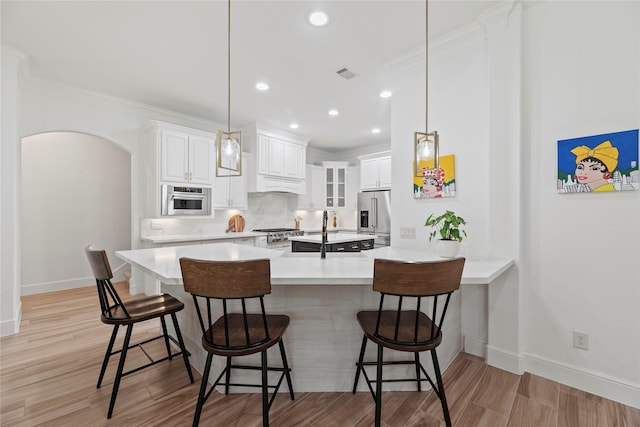 kitchen featuring a breakfast bar area, arched walkways, visible vents, and stainless steel appliances