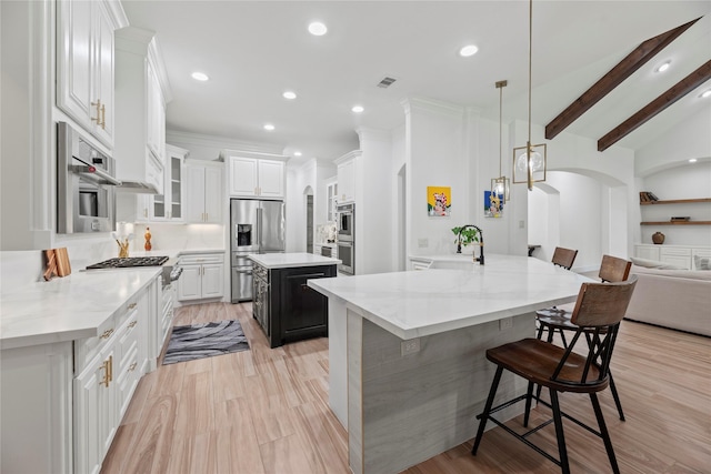 kitchen with visible vents, arched walkways, stainless steel appliances, a kitchen bar, and a center island