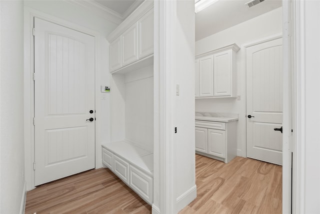 mudroom featuring baseboards, visible vents, light wood finished floors, and ornamental molding