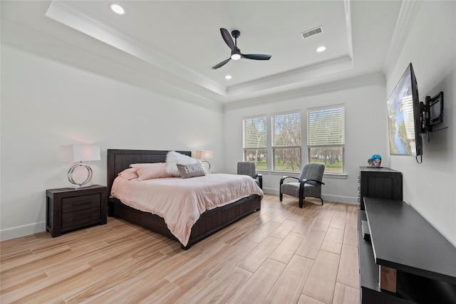 bedroom with a tray ceiling, light wood-style flooring, and crown molding