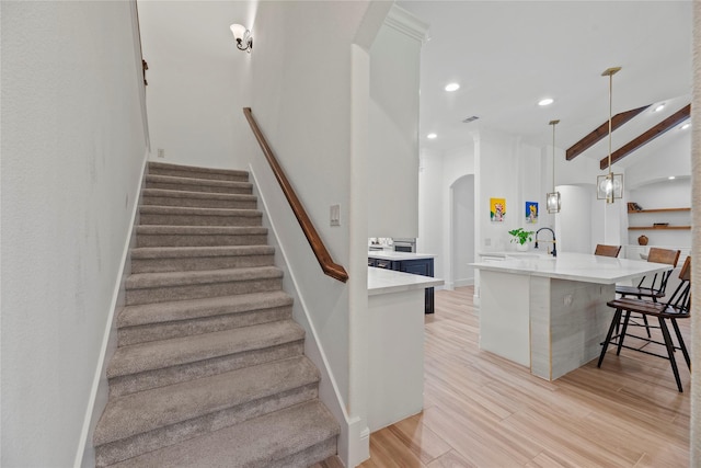 staircase with beamed ceiling, wood finished floors, recessed lighting, arched walkways, and baseboards