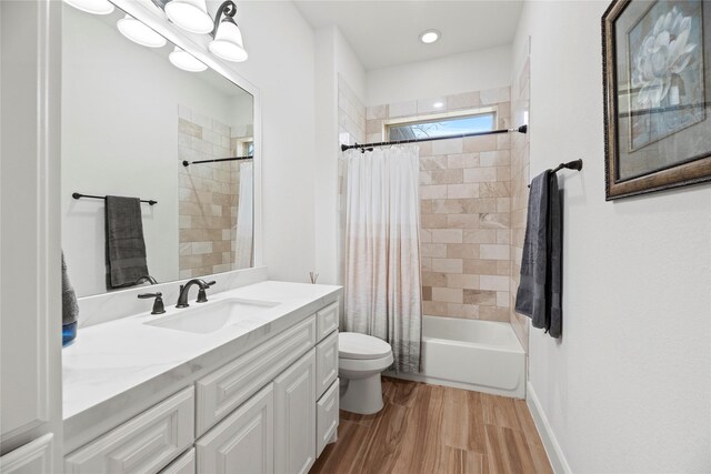 bathroom with toilet, wood finished floors, shower / bath combination with curtain, baseboards, and vanity