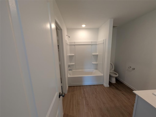 bathroom with vanity, wood finished floors, baseboards, tub / shower combination, and toilet