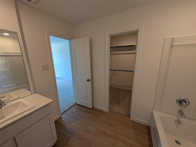 bathroom featuring a spacious closet, visible vents, vanity, and wood finished floors