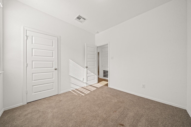 empty room featuring visible vents, baseboards, and carpet