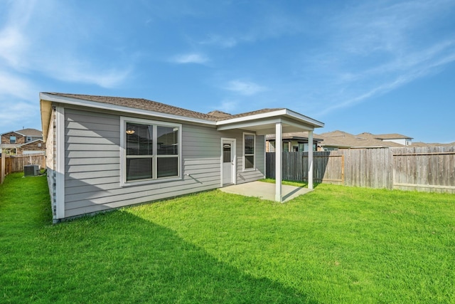 rear view of house with a yard, central AC unit, a fenced backyard, and a patio area