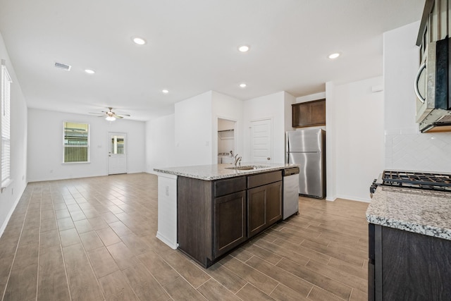 kitchen with visible vents, a sink, dark brown cabinetry, appliances with stainless steel finishes, and decorative backsplash