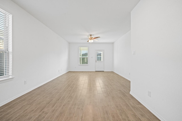 unfurnished living room with a ceiling fan, light wood-type flooring, and baseboards