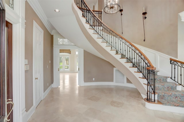 entryway with stairway, recessed lighting, ornamental molding, a towering ceiling, and a decorative wall