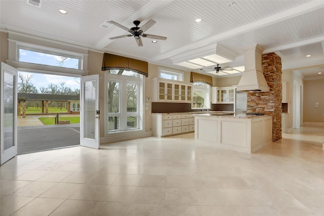 kitchen featuring ceiling fan, custom range hood, glass insert cabinets, beamed ceiling, and backsplash