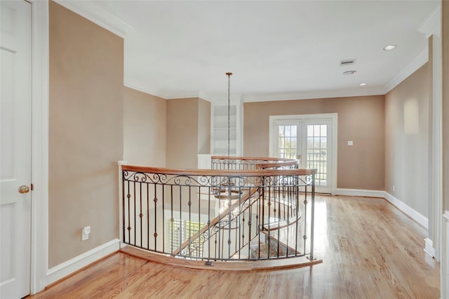 corridor featuring baseboards, an upstairs landing, wood finished floors, and crown molding