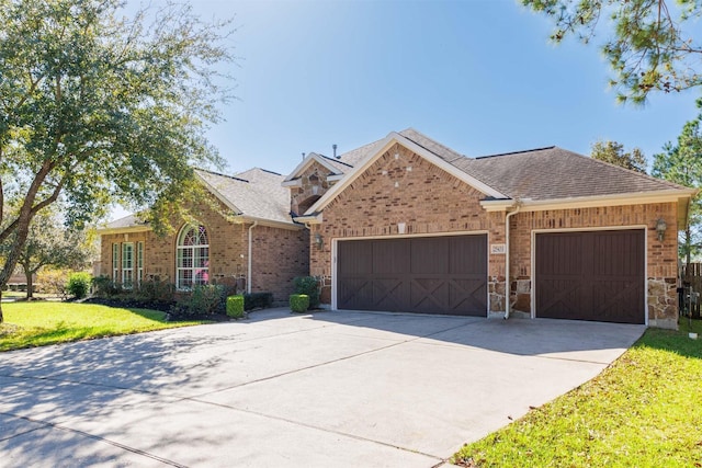 view of front facade with a shingled roof, concrete driveway, a front yard, an attached garage, and brick siding