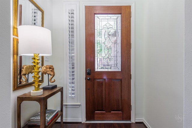 foyer with baseboards and dark wood-style flooring