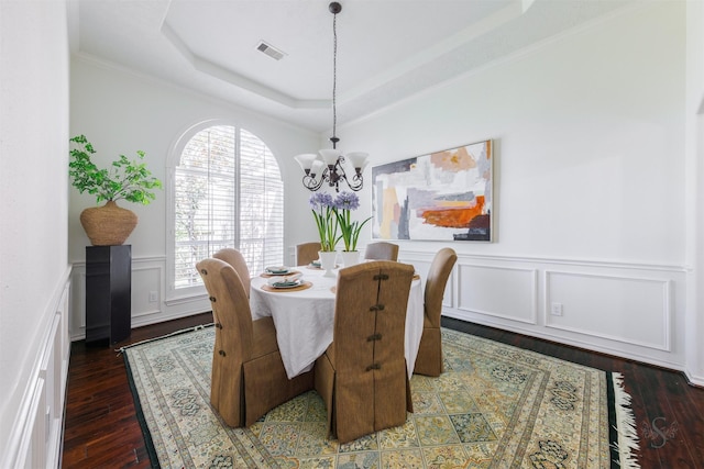 dining space featuring visible vents, an inviting chandelier, a tray ceiling, and hardwood / wood-style flooring