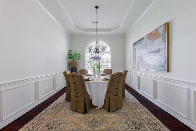 dining space with visible vents, an inviting chandelier, a tray ceiling, and wood finished floors