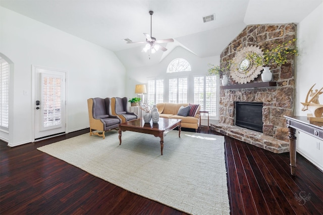 living room with a stone fireplace, wood finished floors, a ceiling fan, and visible vents