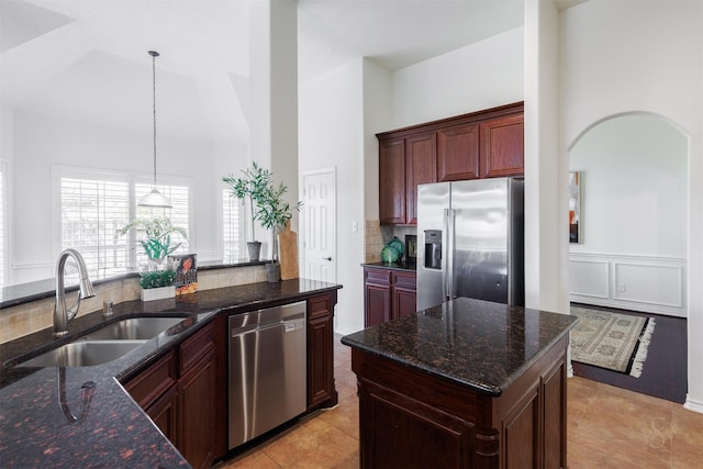 kitchen featuring a sink, decorative light fixtures, dark stone countertops, tasteful backsplash, and appliances with stainless steel finishes