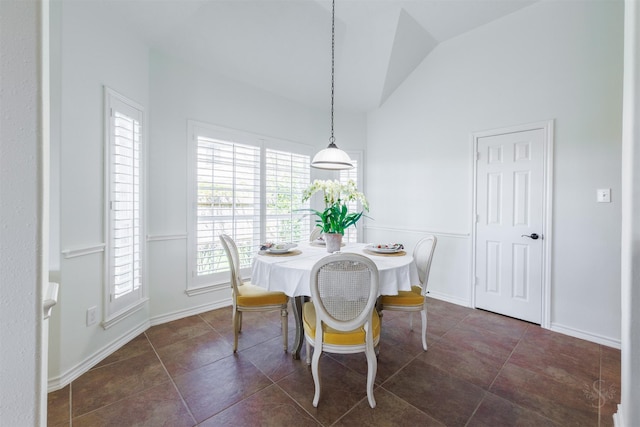 dining space featuring lofted ceiling, dark tile patterned floors, and baseboards