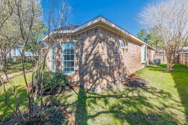 view of property exterior with a yard, brick siding, cooling unit, and fence