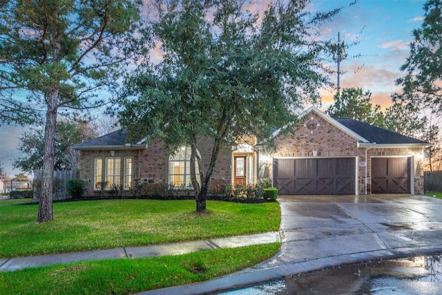 view of front of property with brick siding, fence, concrete driveway, a front yard, and a garage