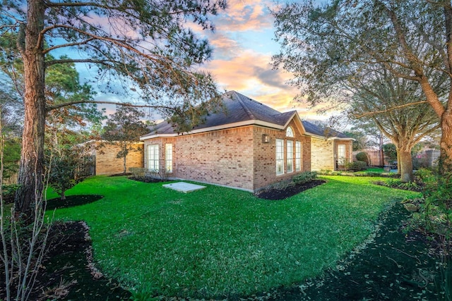 view of property exterior with a yard, brick siding, french doors, and fence